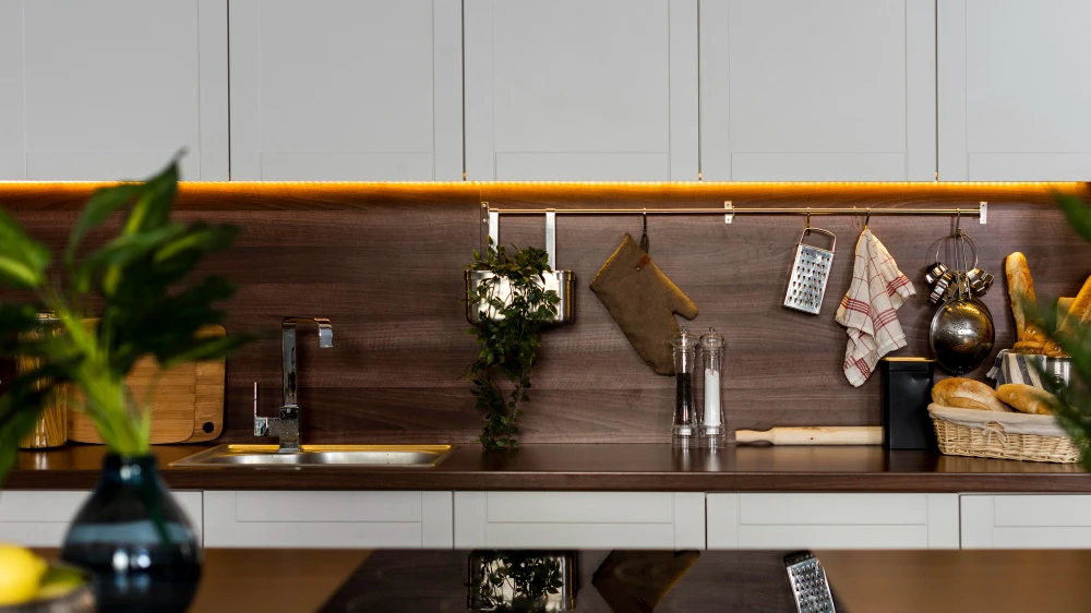 Imagem de uma cozinha compacta e criativa com armários brancos, bancada em madeira, utensílios organizados e iluminação moderna, ideal para inspirações de cozinhas compactas e criativas.