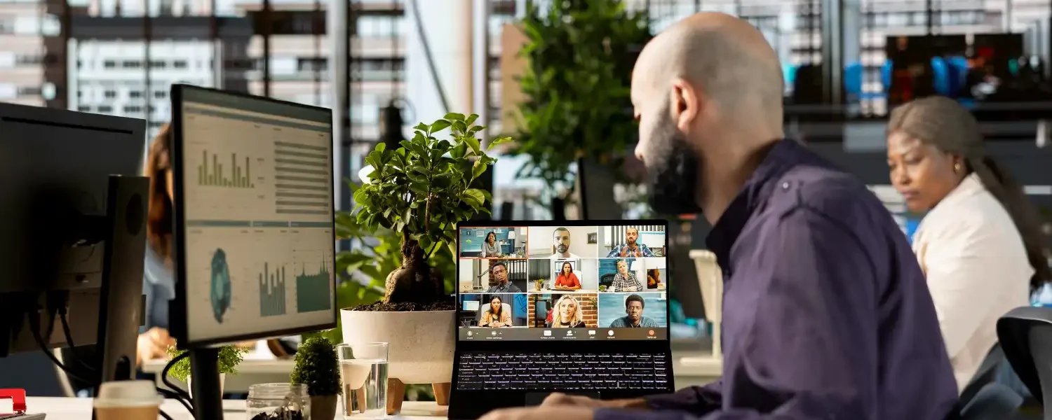 Imagem de uma equipe de profissionais trabalhando em um escritório moderno, utilizando monitoramento em tempo real e lideranças à distância com videoconferências e análise de dados.
