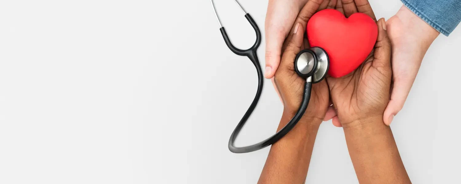 Saúde preventiva: Quais hábitos podem contribuir para uma rotina mais equilibrada: Mãos segurando um coração vermelho com estetoscópio ao lado, simbolizando Saúde preventiva e hábitos para uma rotina mais equilibrada e saudável.